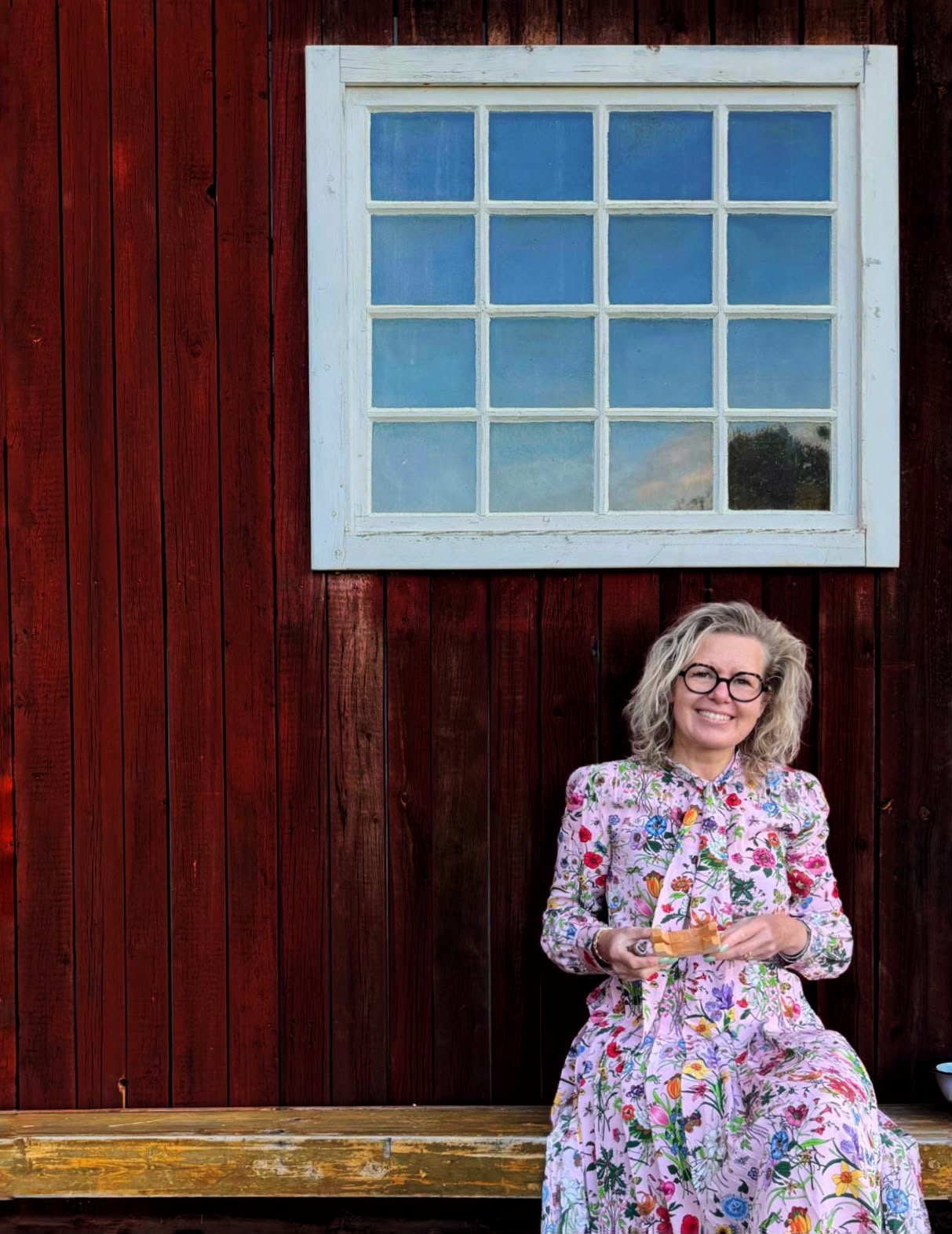 Elske in a floral dress outside the red guesthouse wall