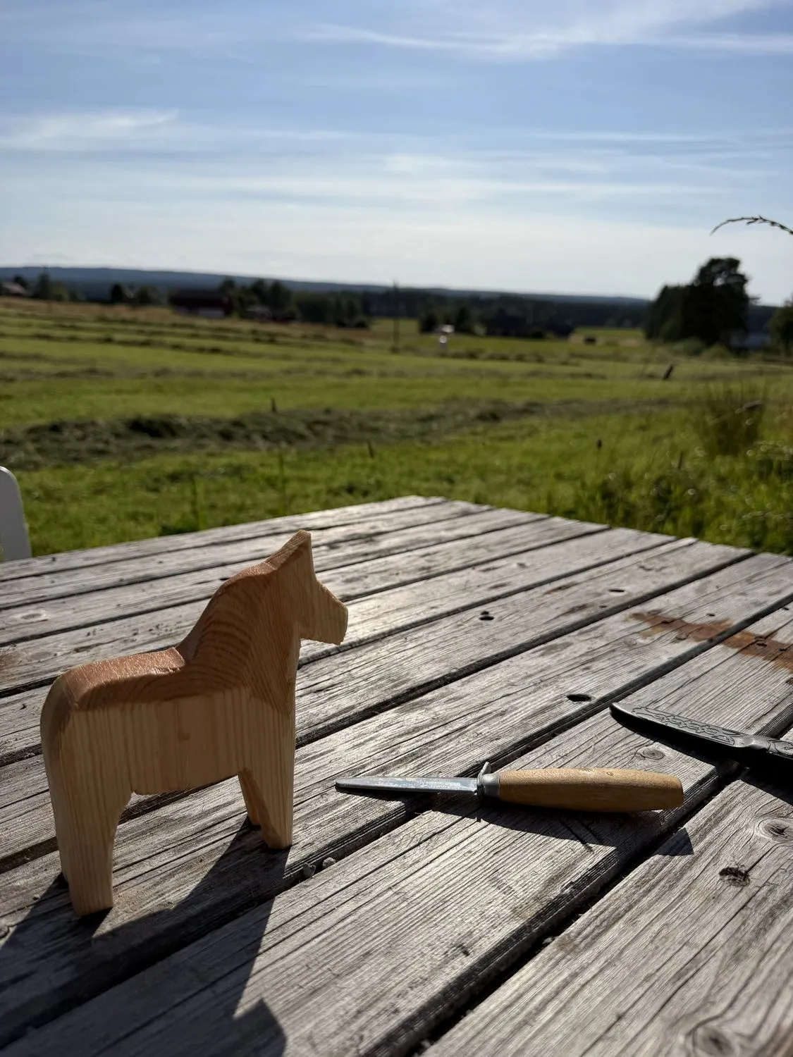 A hand-carved Dala horse on the weathered wooden deck