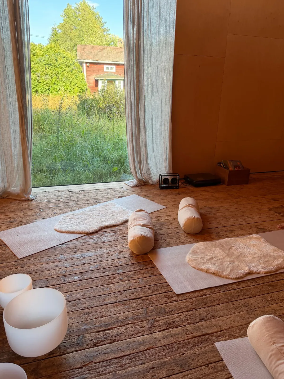 A quiet yoga room with sheepskins and singing bowls by the open window