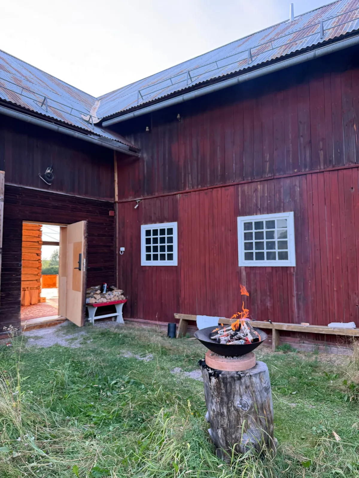 A fire bowl in the grass courtyard between the red timber buildings